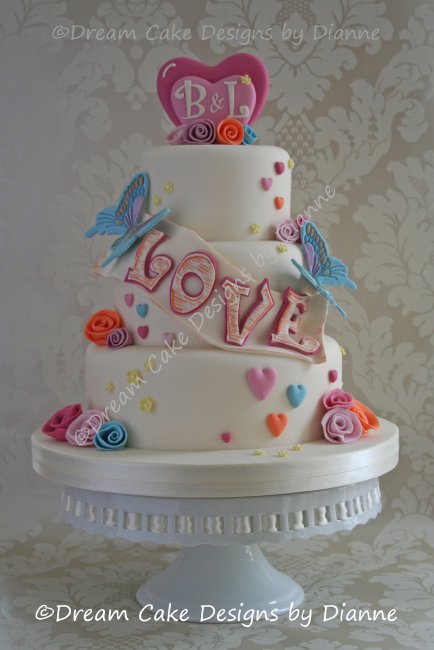 3 tier 'LOVE' Wedding Cake decorated with butterflies, hearts and rolled ribbon roses with a love heart monogram cake topper - Dream Cake Designs (Dianne Stanley)