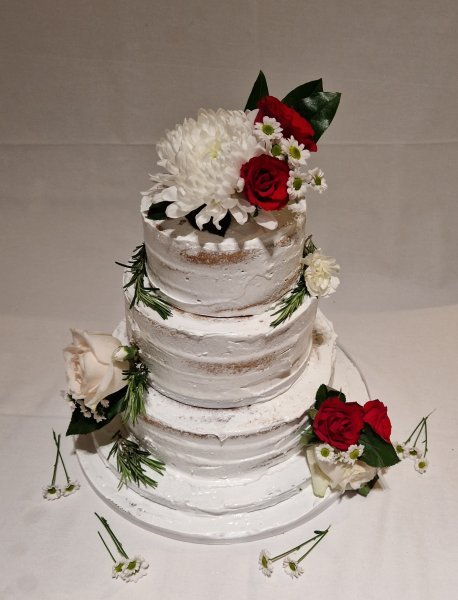 3 tier swiss meringue covered cake with fresh flowers. - Speciality-Cakes