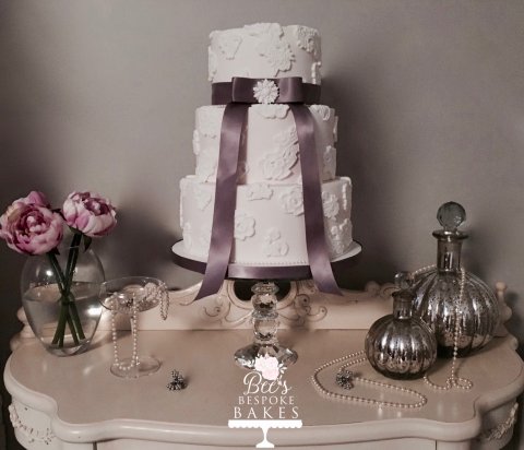 Graceful three tier wedding cake decorated with edible applique lace, grey ribbon and an edible brooch - Bee's Bespoke Bakes