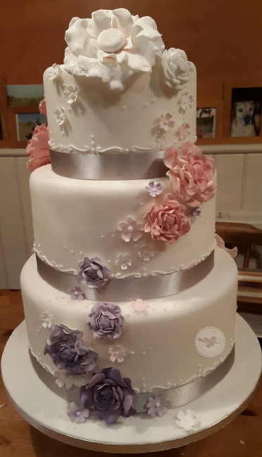 Trailing open roses in pastel colours decorate this pretty cake - Sophisticakes 