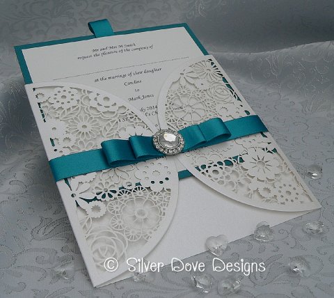 Opulence - a beautiful laser cut invitation surrounded by a lovely double satin ribbon finished with a dior style bow and a lovely crystal style embellishment - Silver Dove Wedding Stationery