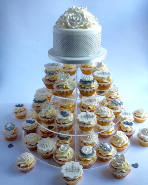 Moon River. nspired by the twentieth century style icon Audrey Hepburn, this timeless classic wedding cupcake tower will be an elegant centre piece for any wedding reception and YES all of those dots on the top tier cake are hand piped, promise, no fibs! The cupcakes add that extra bit of glamour with a mixture of hand crafted brooches and soft sugar roses and there are ample cupcakes to fill the stand so you can use the extra ones to add some pretty confetti additions to your cake table - Karen's Cakes 