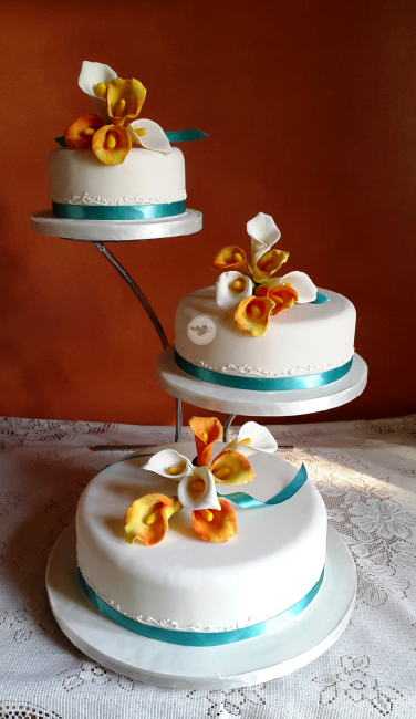 Sprays of Calla lilies decorate this cake displayed on an offset stand. - Sophisticakes 