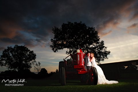Bride and groom posing with a tractor. Country wedding. - Martin Hill Photography 