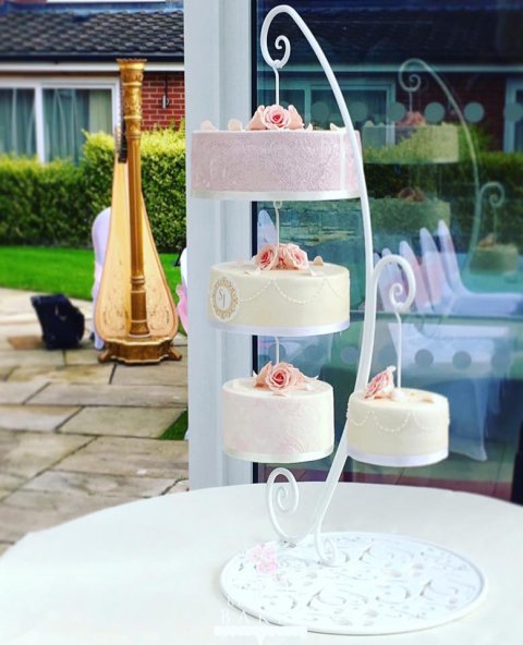 Beautiful chandelier wedding cake, with edible cake lace, monogrammed plaque, damask stencilling and hand piping in blush pink, champagne and white. Hung from a gorgeous custom made stand. - Bee's Bespoke Bakes